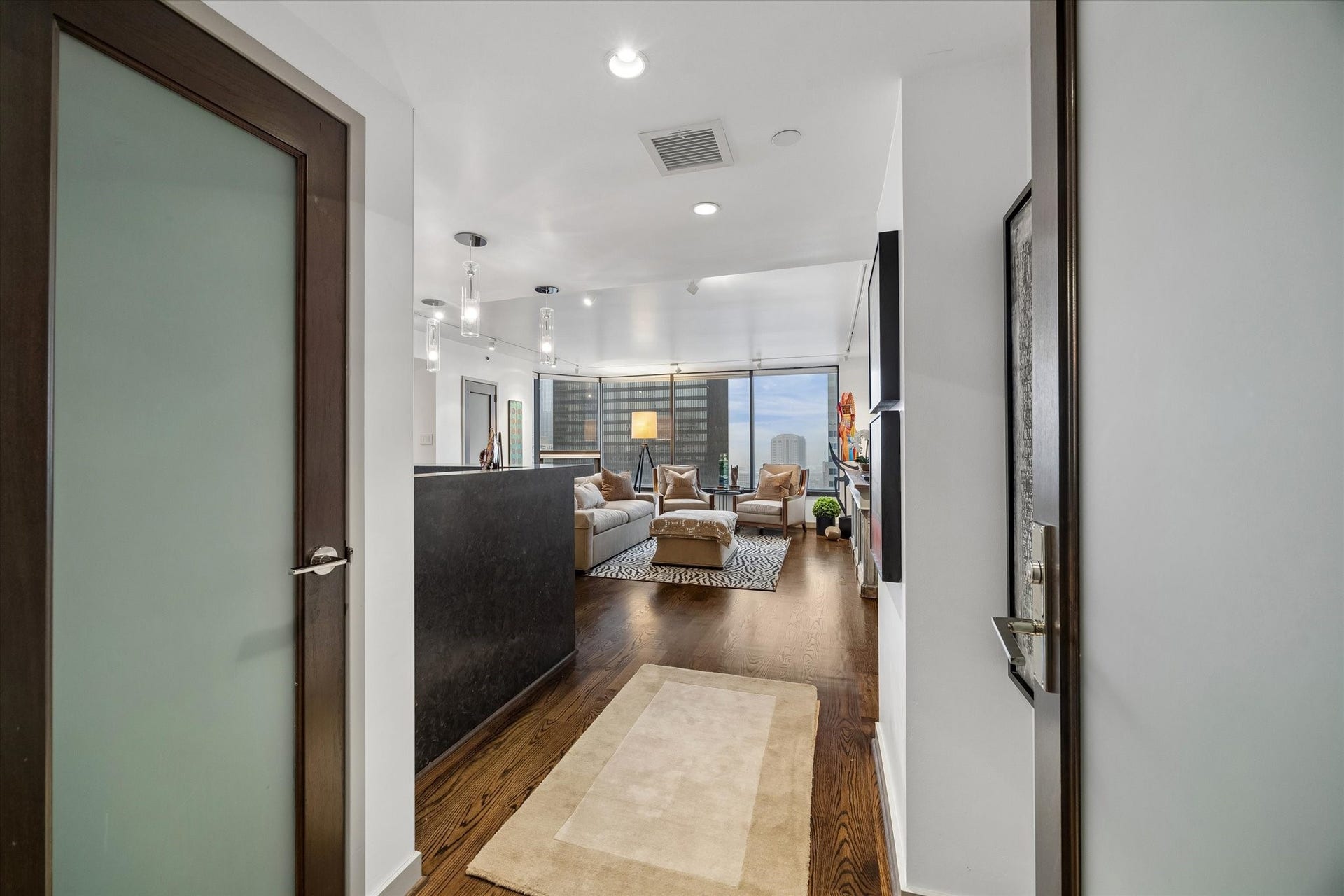 1111 Caroline Street, #2601, Houston, TX 77010 Entry corridor leads directly into the living area, with frosted glass door inserts carrying light between interior spaces. Nearby closet storage keeps everyday essentials close to the entrance.