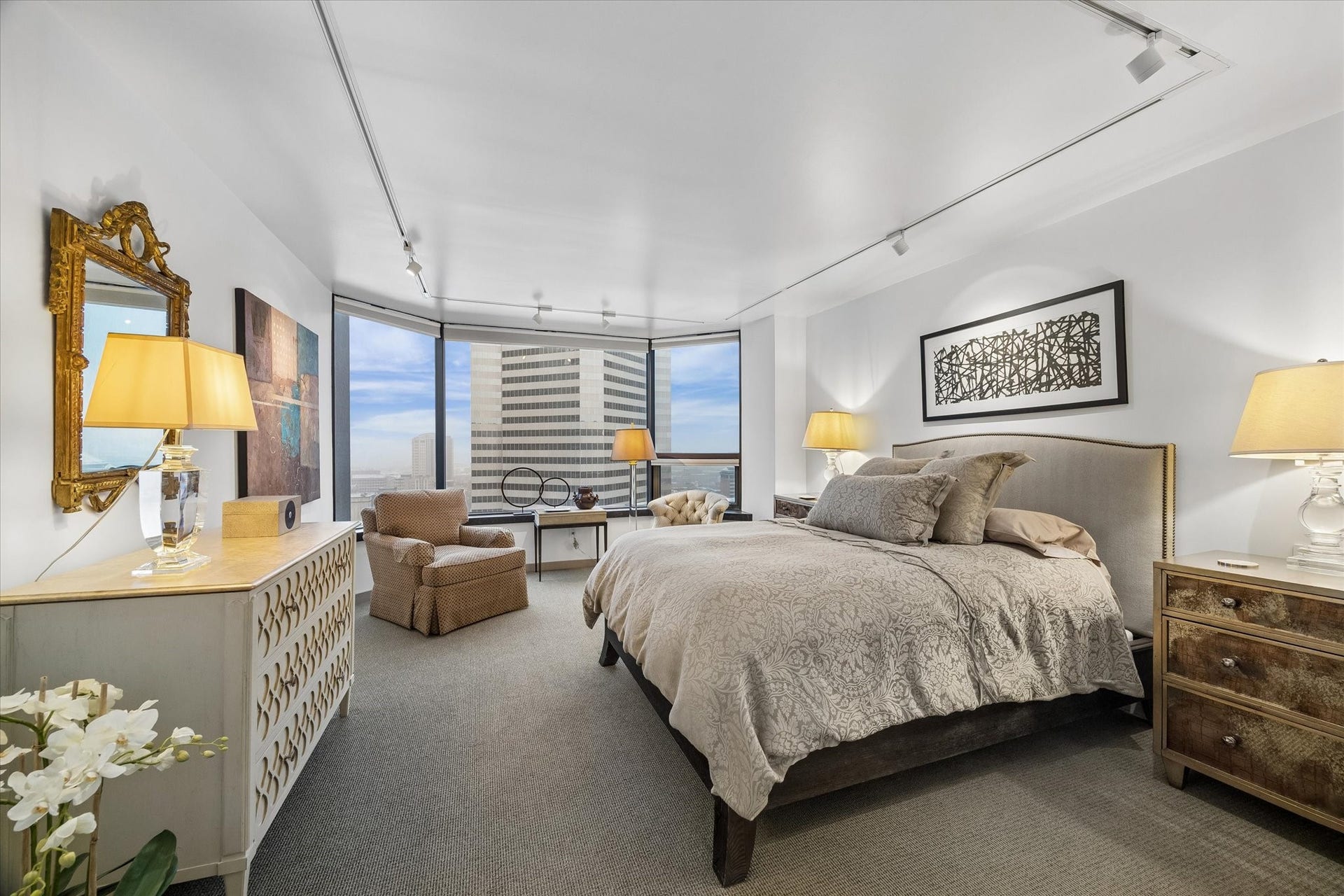 1111 Caroline Street, #2601, Houston, TX 77010 Bedroom windows frame the downtown skyline, with automated Lutron shades for light control and privacy. Carpet distinguishes the sleeping area from the wood floors in the main living space.