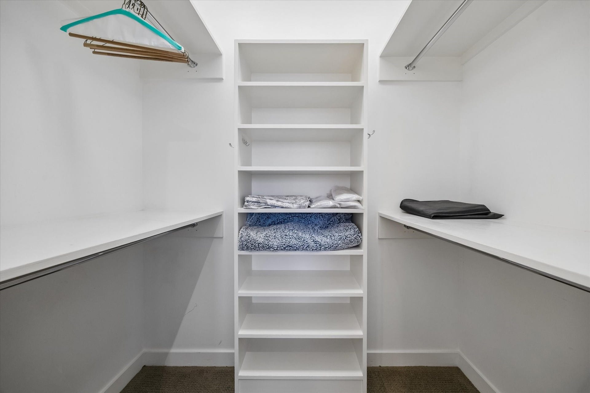 1111 Caroline Street, #2601, Houston, TX 77010 Shelving and hanging rails line both sides of the walk in closet, separating folded items from hanging storage and keeping the center aisle clear.