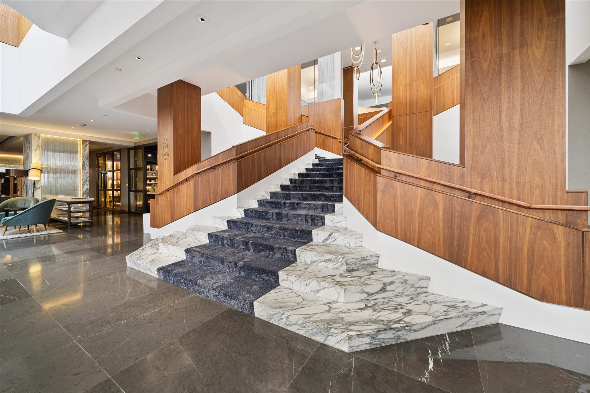 1111 Caroline Street, #2601, Houston, TX 77010 Sculptural staircase links levels within the hotel lobby. Stone surfaces, wood accents and open landings make the vertical connection a central feature of the space.