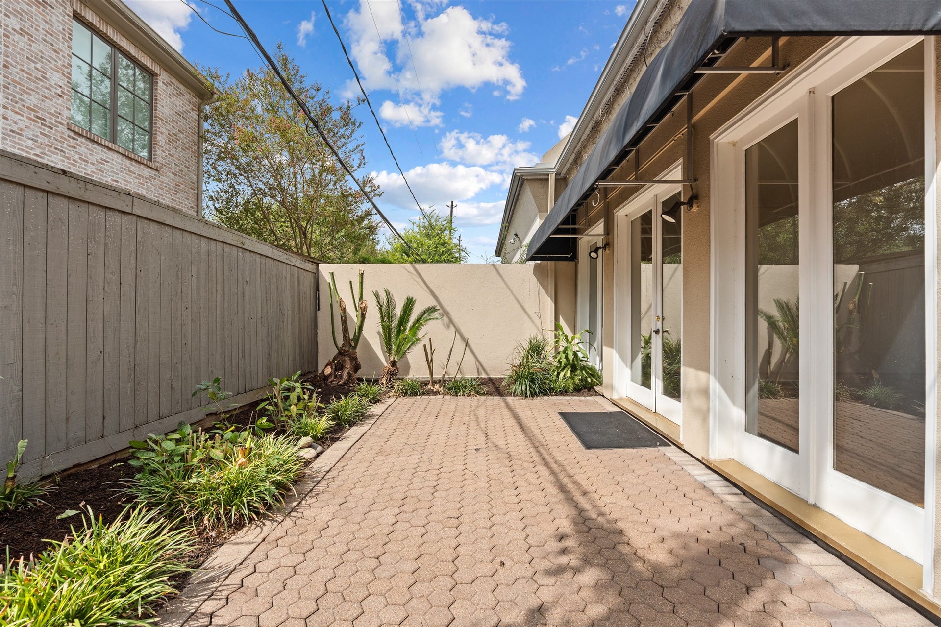 3923 Childress Street, #A, Houston, TX 77005 Charming back private patio with brick pavers, lush landscaping, and elegant French doors, perfect for outdoor relaxation and entertainment.