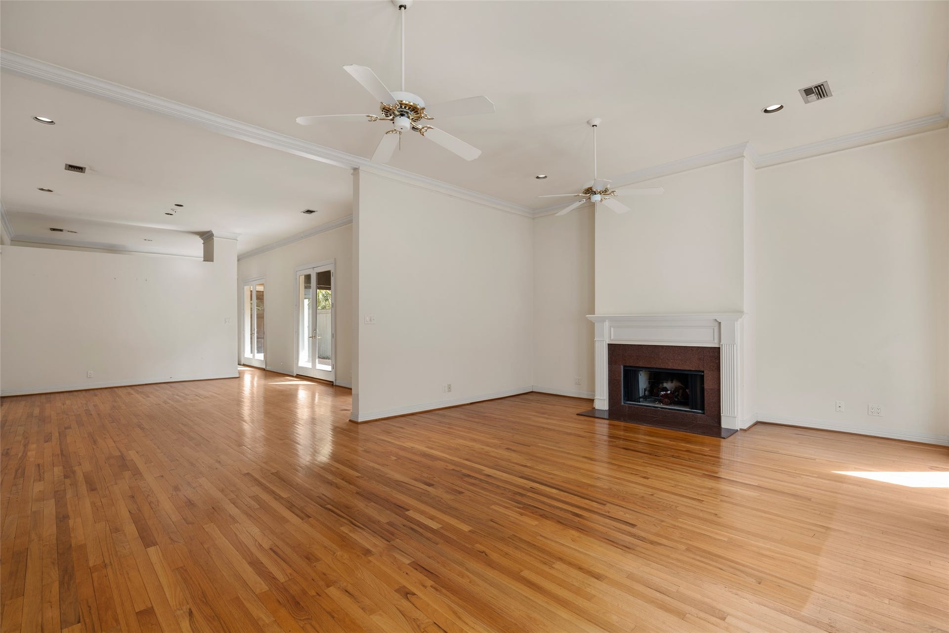 3923 Childress Street, #A, Houston, TX 77005 Spacious and bright living area with polished hardwood floors, a cozy fireplace, leading to a sunlit outdoor space through glass doors.