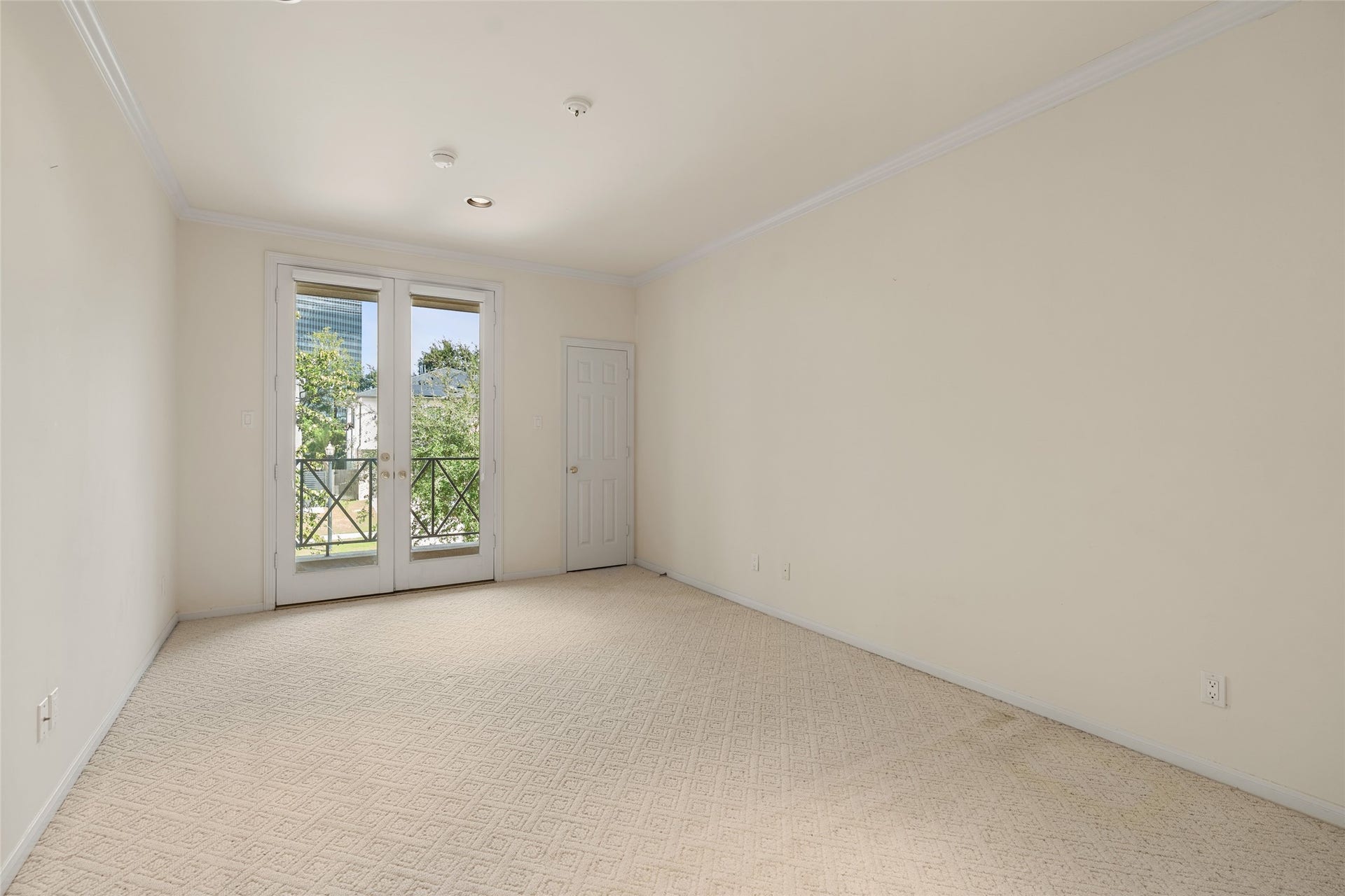 3923 Childress Street, #A, Houston, TX 77005 Bright and spacious room featuring elegant French doors that open to a charming balcony, offering a serene view of lush greenery.
