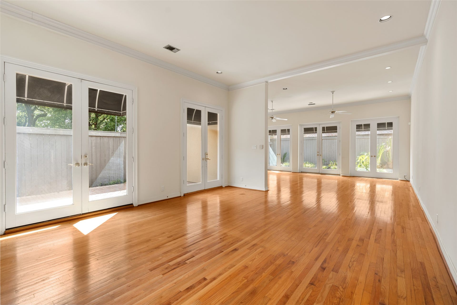 3923 Childress Street, #A, Houston, TX 77005 Spacious and bright open living area with gleaming hardwood floors, abundant natural light from multiple French doors, and elegant ceiling fans.
