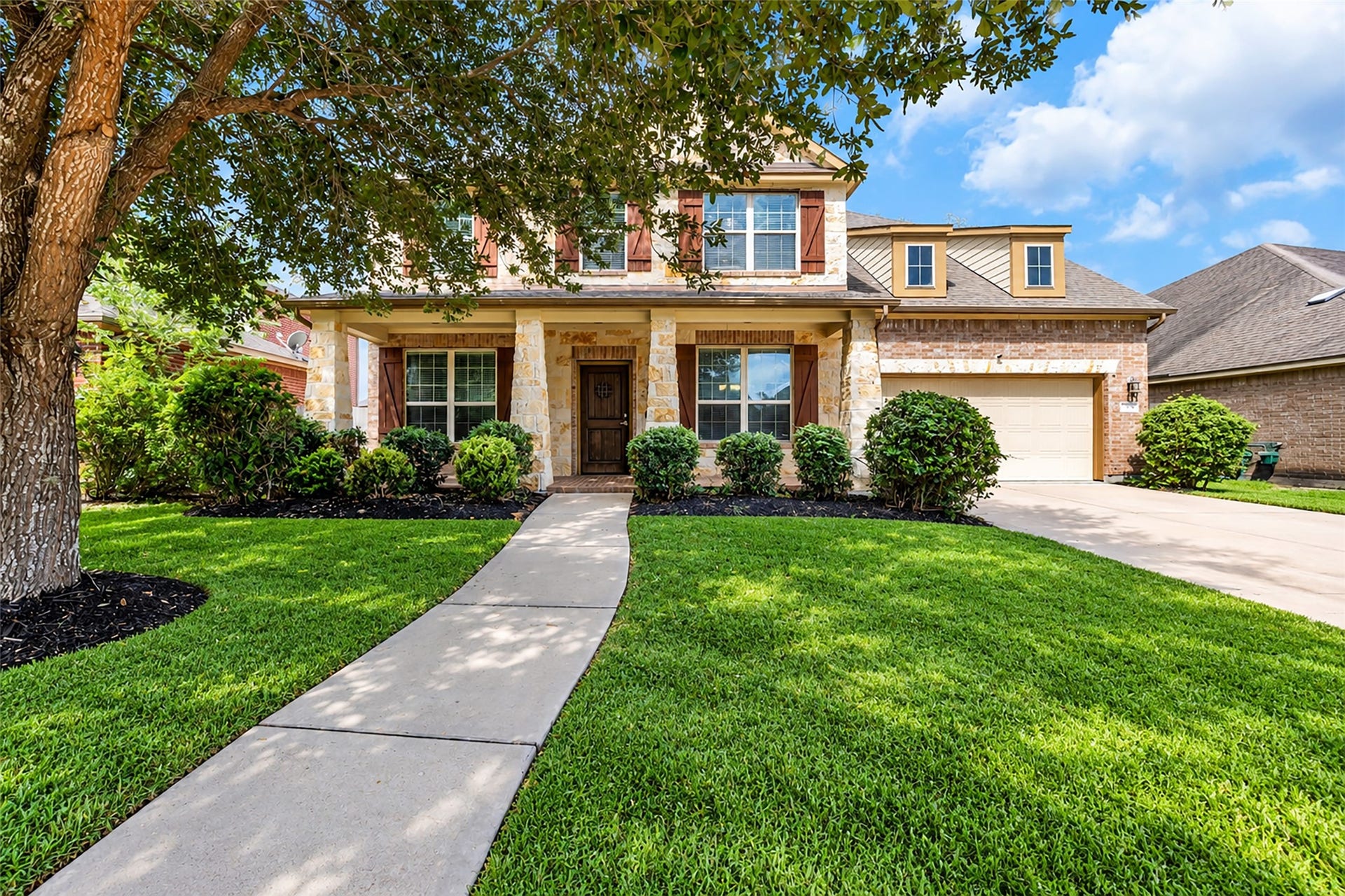 7 Ember Branch Drive, Missouri City, TX 77459 Curb appeal from every angle, with stone accents, shutters, manicured landscaping and an attached two-car garage.