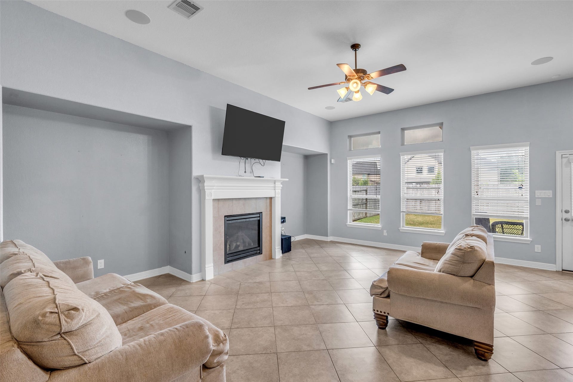 7 Ember Branch Drive, Missouri City, TX 77459 Tall windows with transoms fill the living room with natural light, with built-in niches framing the fireplace.