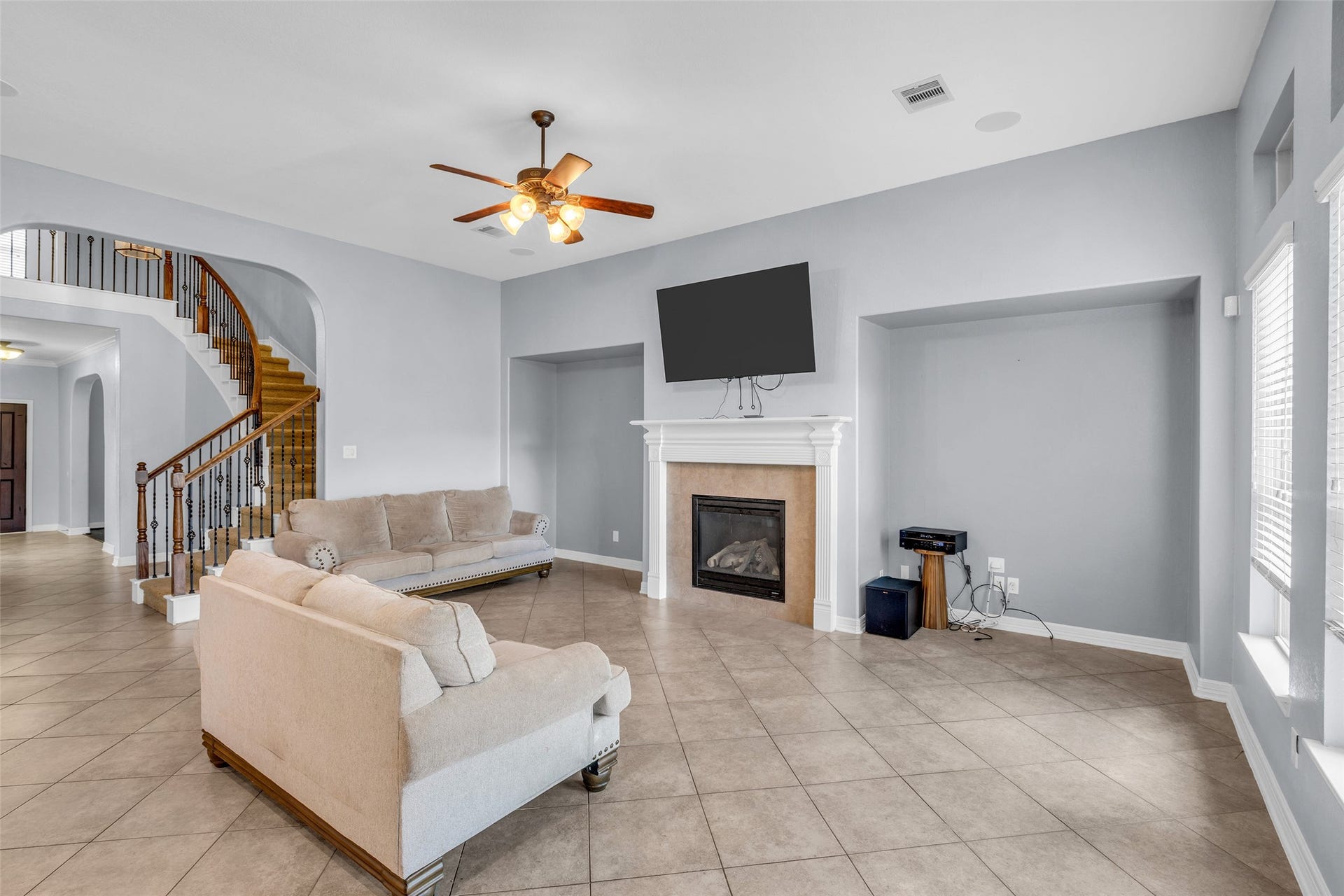 7 Ember Branch Drive, Missouri City, TX 77459 Gather around the gas fireplace in a spacious living room, with a curved staircase and wrought-iron railing as the backdrop.