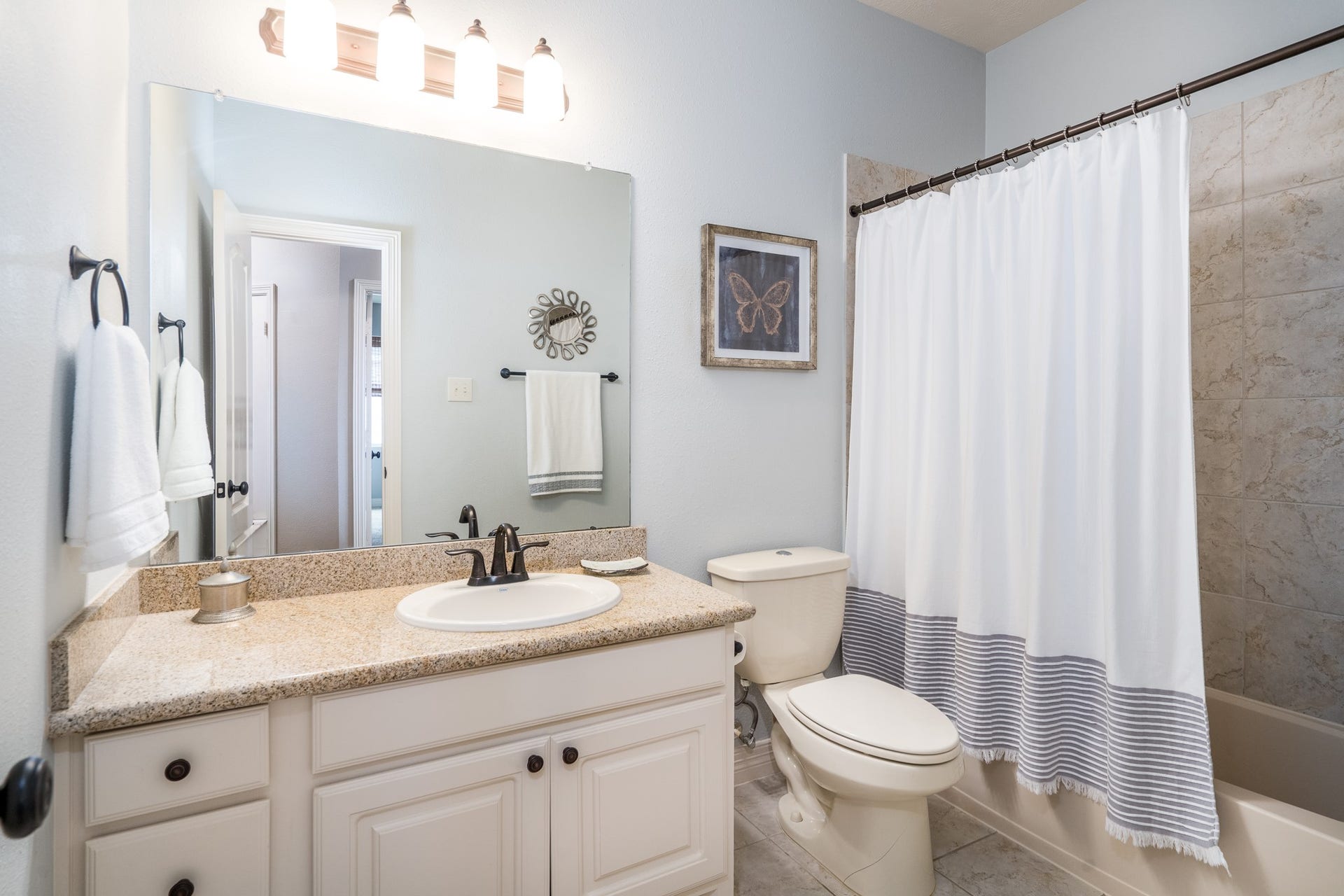 Located across from the fifth bedroom is this full bath with granite countertops, a tub/shower combo with tile surround, and plenty of storage!