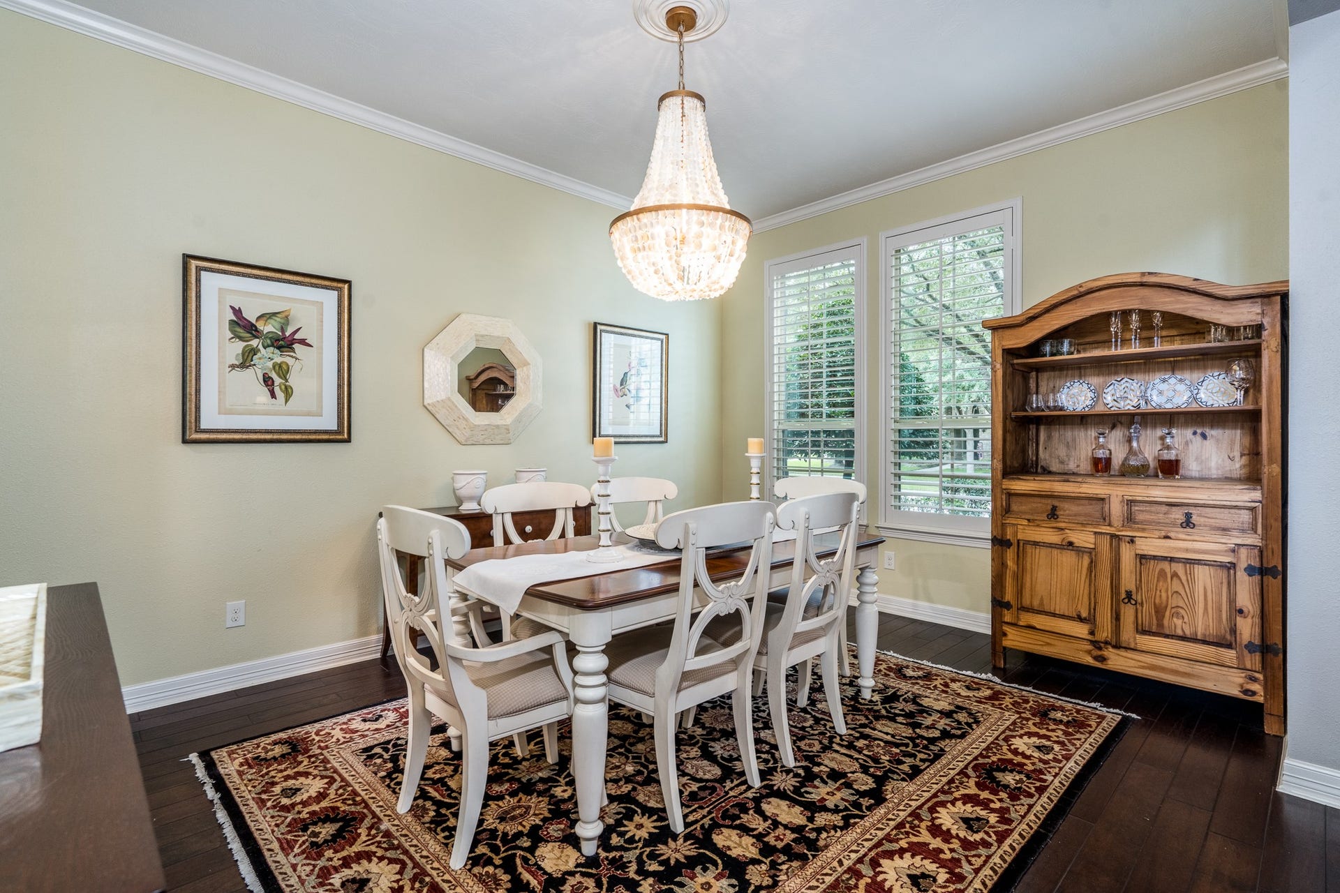 To the right of the entry is this timeless dining room that boasts hardwood floors, plantation shutters, crown molding and a custom chandelier! Imagine gathering in this serene space for special meals!