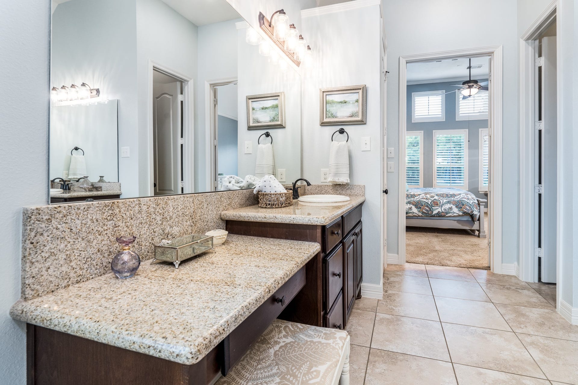 Dual vanity sinks, one with knee space, provide abundant cabinets for storage. Double doors offer easy access to the primary bedroom from this elegant bath!