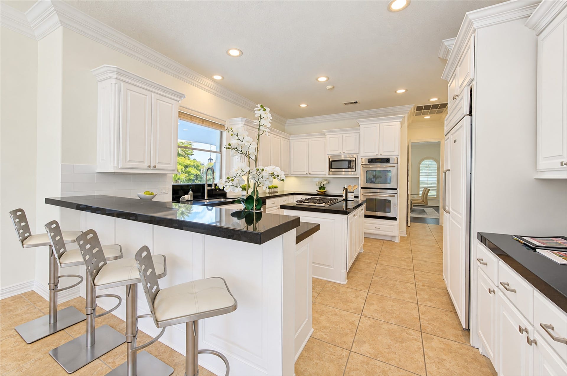 14014 Hampton Cove Drive, Houston, TX 77077 Beautifully revamped kitchen featuring an open-concept layout, abundant custom cabinetry, and dual pantries. The space flows seamlessly into the main gathering area and offers stunning views of the backyard pool.