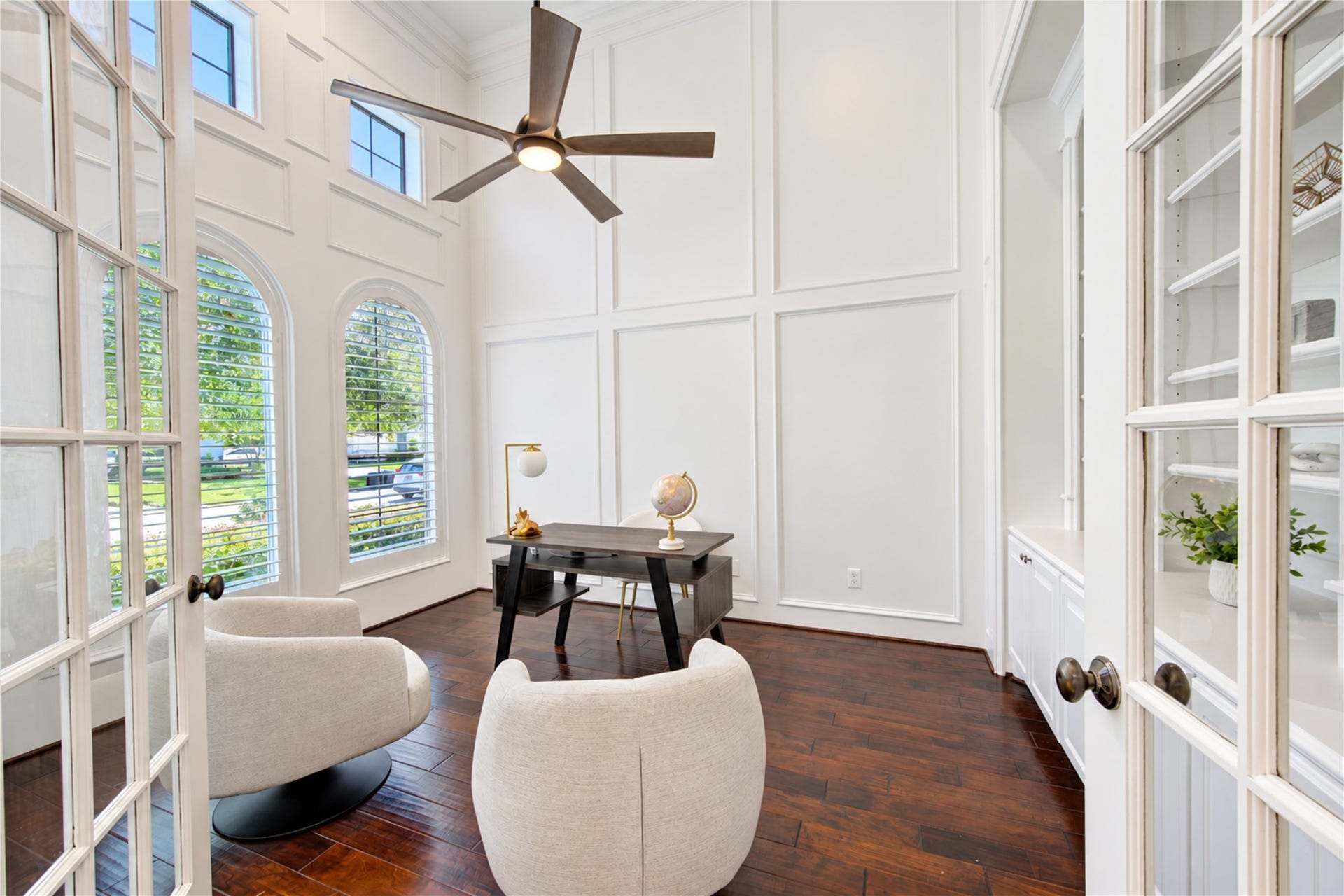 14014 Hampton Cove Drive, Houston, TX 77077 This home office has been completely renovated, featuring pristine finishes, soaring high ceilings, and custom built-in bookshelves. The space is filled with natural light, complemented by elegant shutters for a bright and airy feel.
