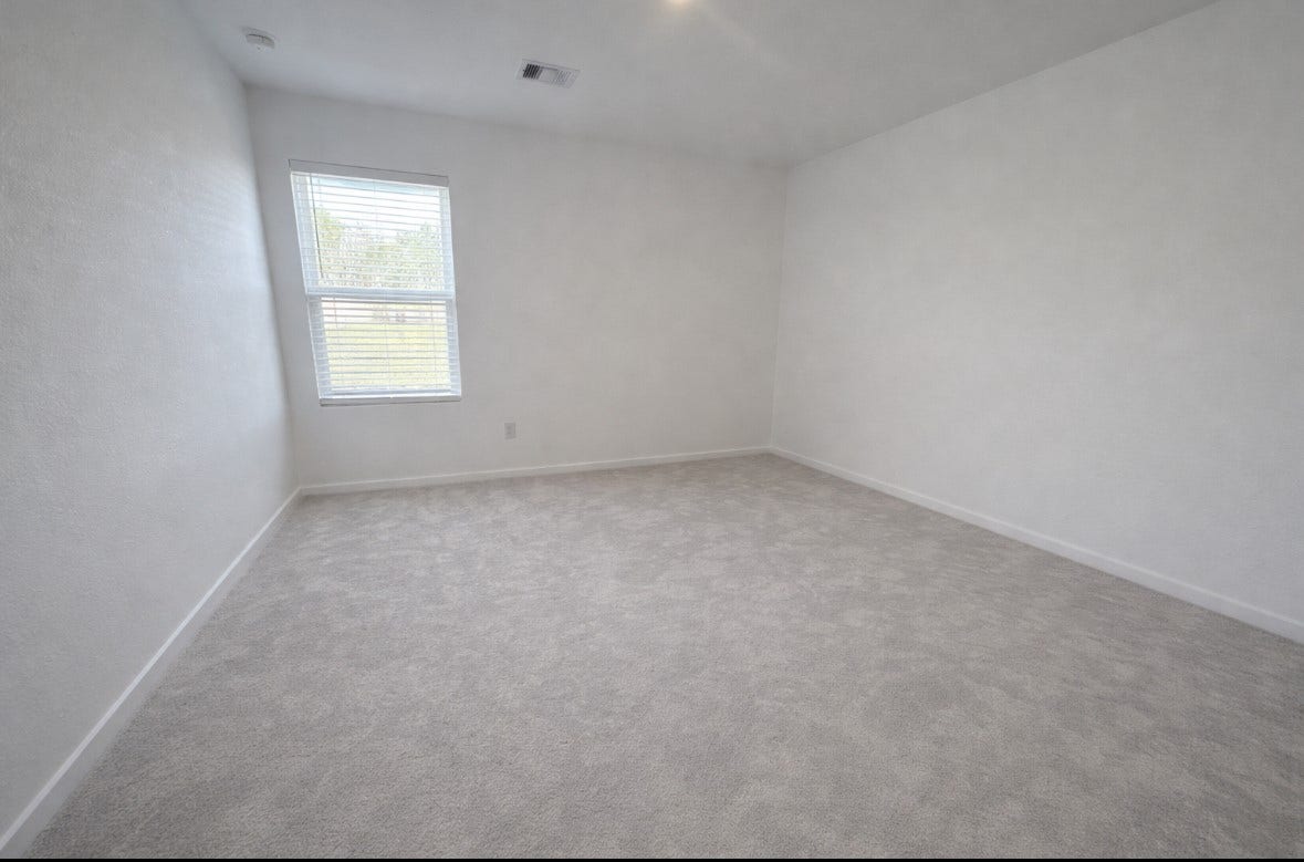 21151 Vercelli, New Caney, TX 77357 This photo showcases a bright, empty room with light-colored carpet and walls, featuring a window that lets in natural light. The space is versatile and ready for personalization.