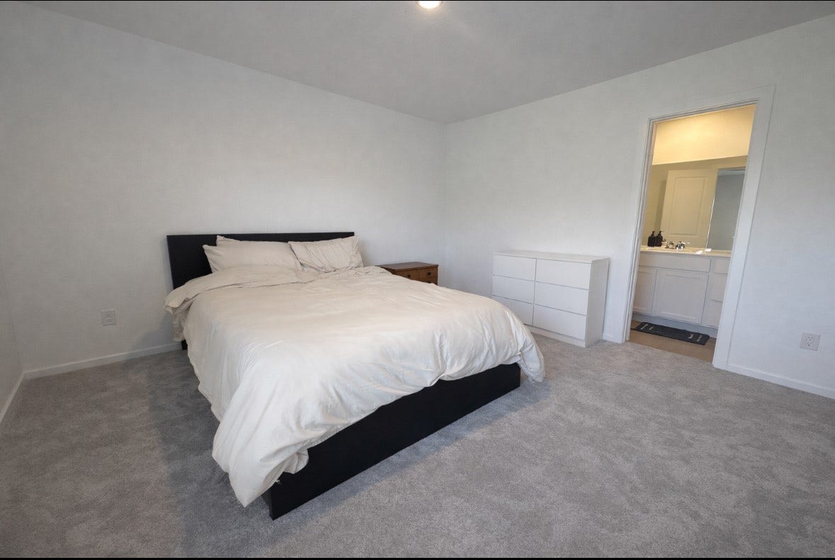 21151 Vercelli, New Caney, TX 77357 This spacious bedroom features a comfortable bed, neutral carpet, and minimalistic decor. It includes a small dresser and connects to a bright en-suite bathroom, offering convenience and privacy.