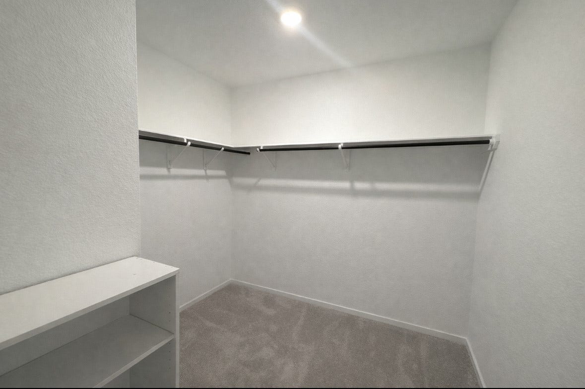 21151 Vercelli, New Caney, TX 77357 Spacious walk-in closet with neutral carpeting, built-in shelving, and ample hanging space, perfect for organized storage.