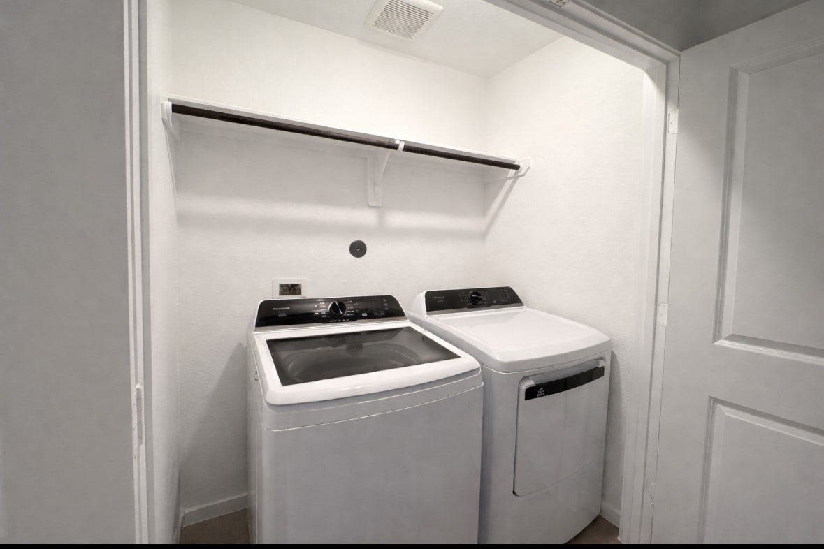21151 Vercelli, New Caney, TX 77357 This photo shows a compact laundry area with a modern washer and dryer set, a shelf above for storage, and bright white walls.
