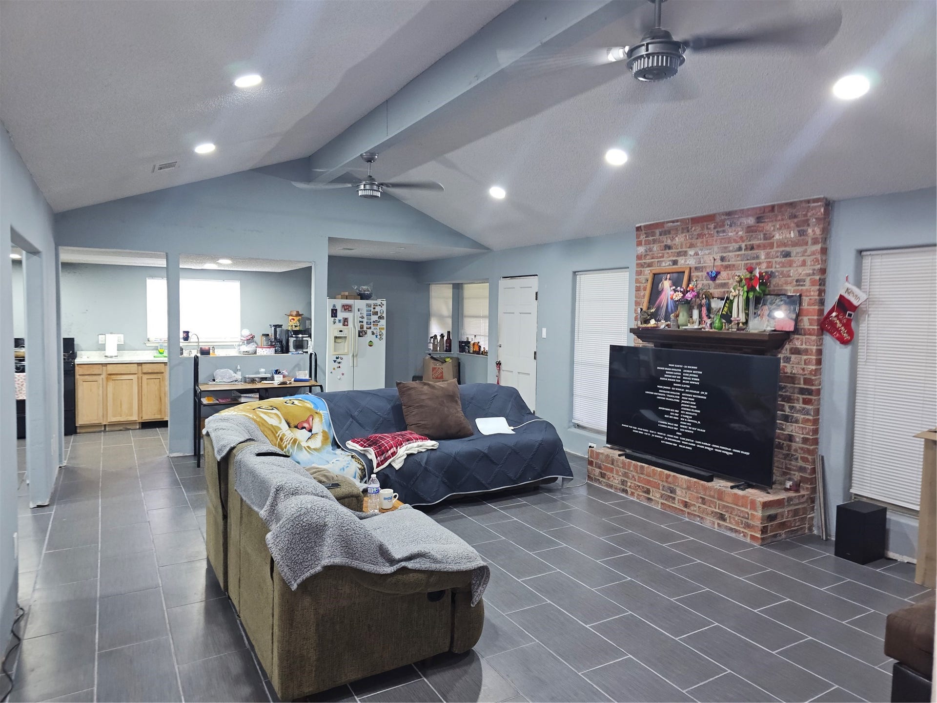 909 Lilac Street, La Marque, TX 77568 Open-concept living area features vaulted ceilings, a classic brick fireplace, tile flooring, and abundant natural light.