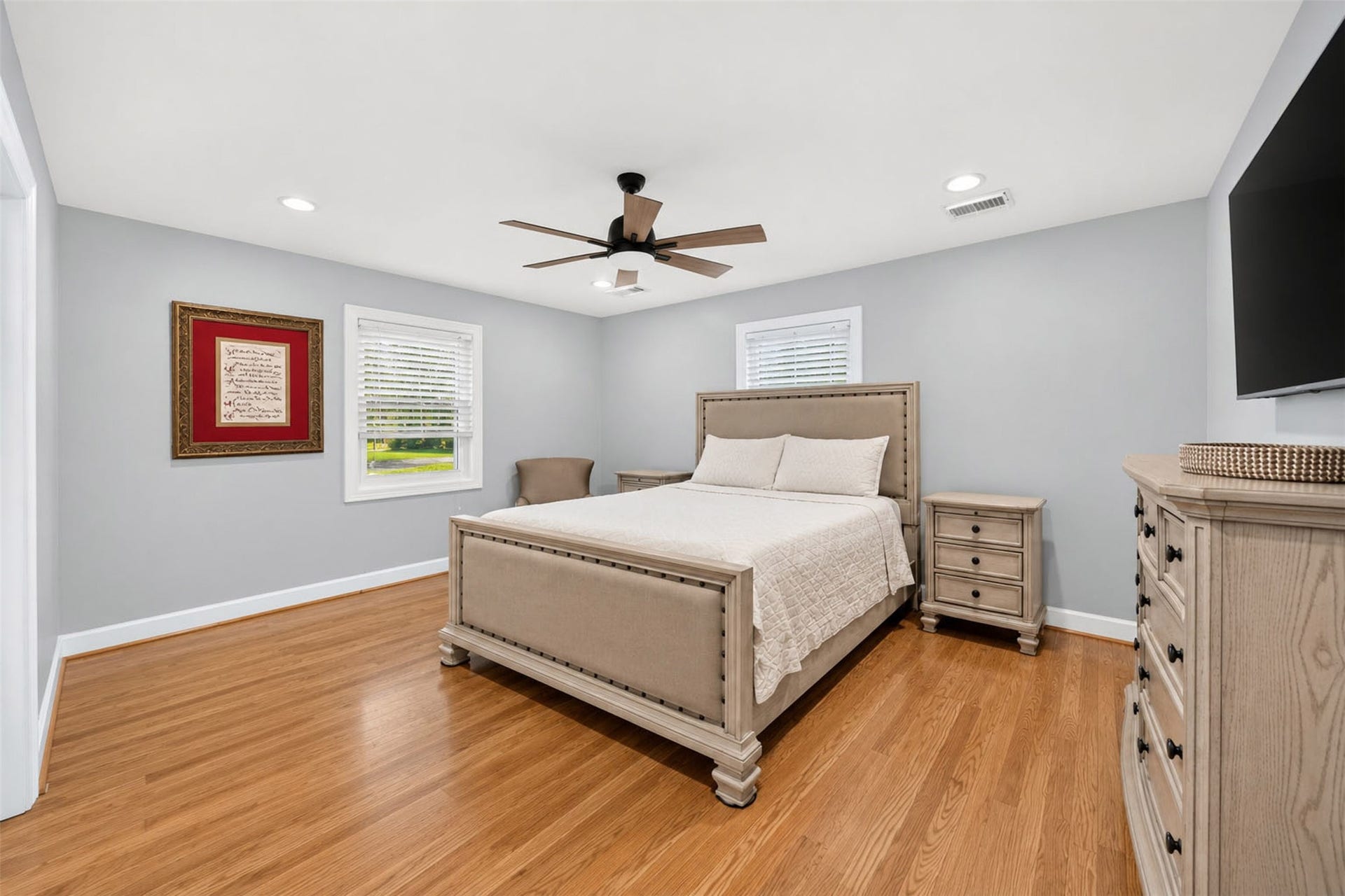 Bedroom features wood-look flooring, two windows, recessed lighting, and a ceiling fan.