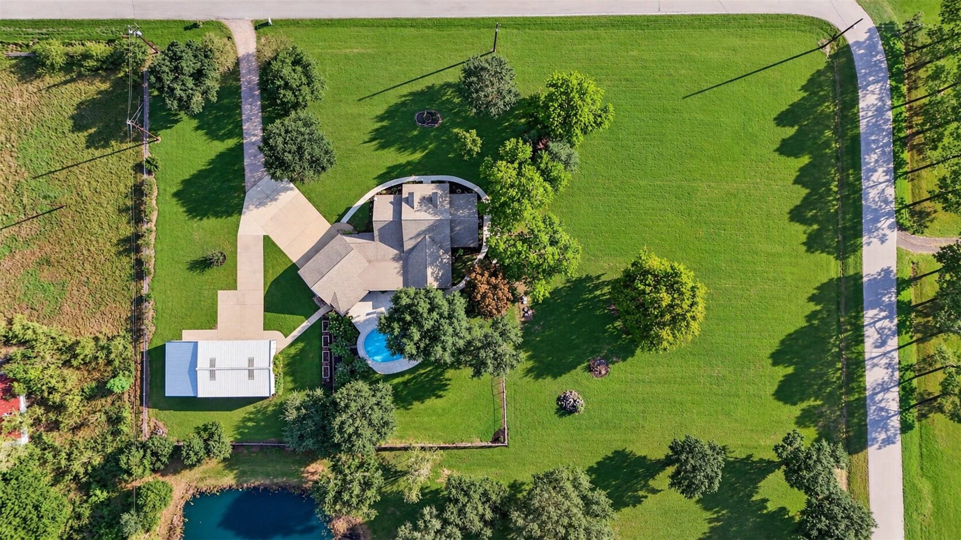 Overhead view illustrates the arrangement of the home, pool, detached building, driveway, and mature trees.