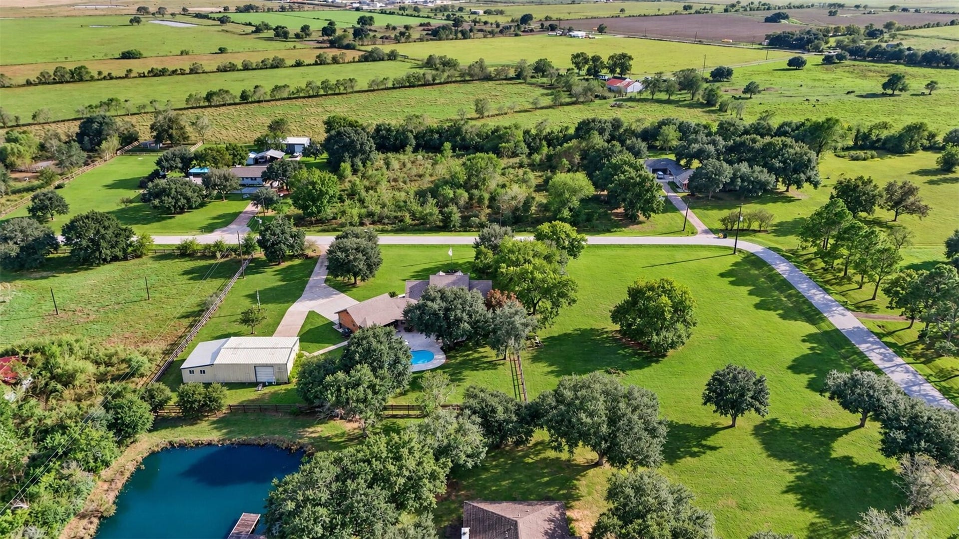 Elevated rear view places the home, pool, and detached building within the surrounding rural landscape.