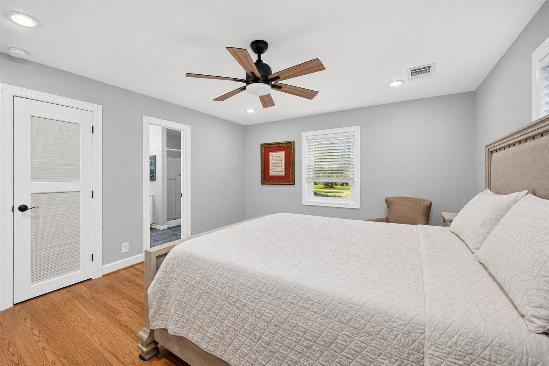Additional bedroom view shows a louvered door, lawn views, and direct access to an adjoining bathroom.