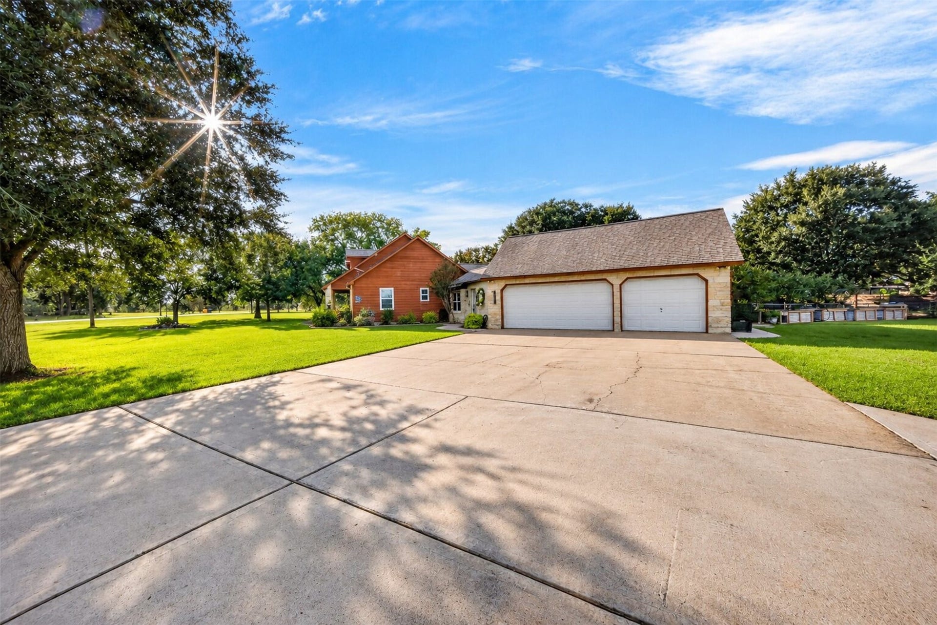 Three-car attached garage with a wide concrete driveway and surrounding lawn.