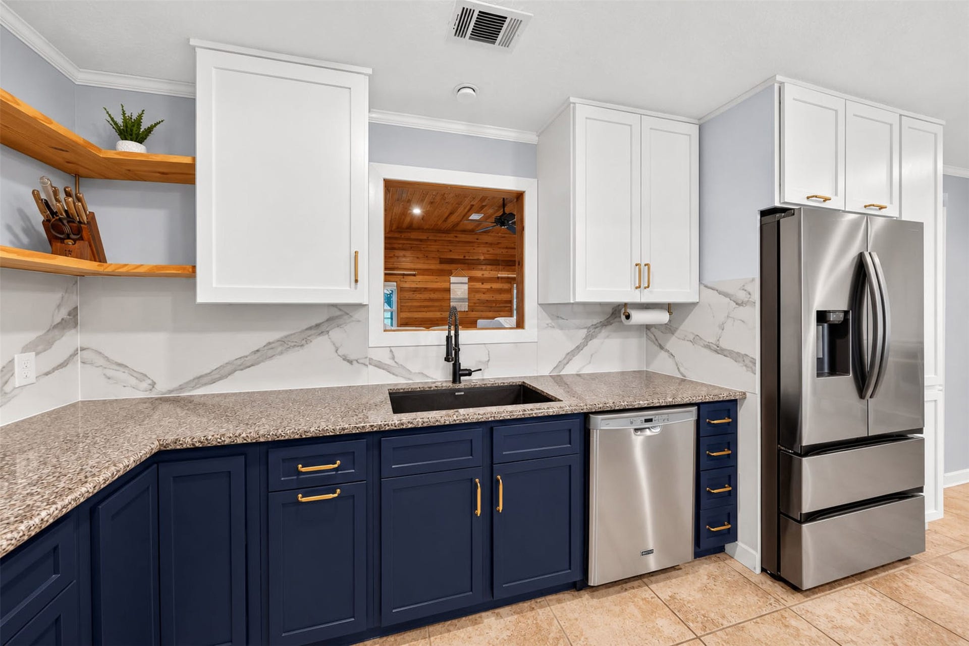 Kitchen sink area includes a tall black faucet, stainless dishwasher, and pass-through to the adjoining living room.
