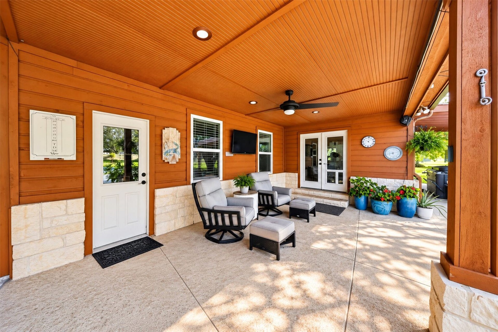 Sheltered patio seating area with recessed lighting, a ceiling fan, and glass-paneled doors.
