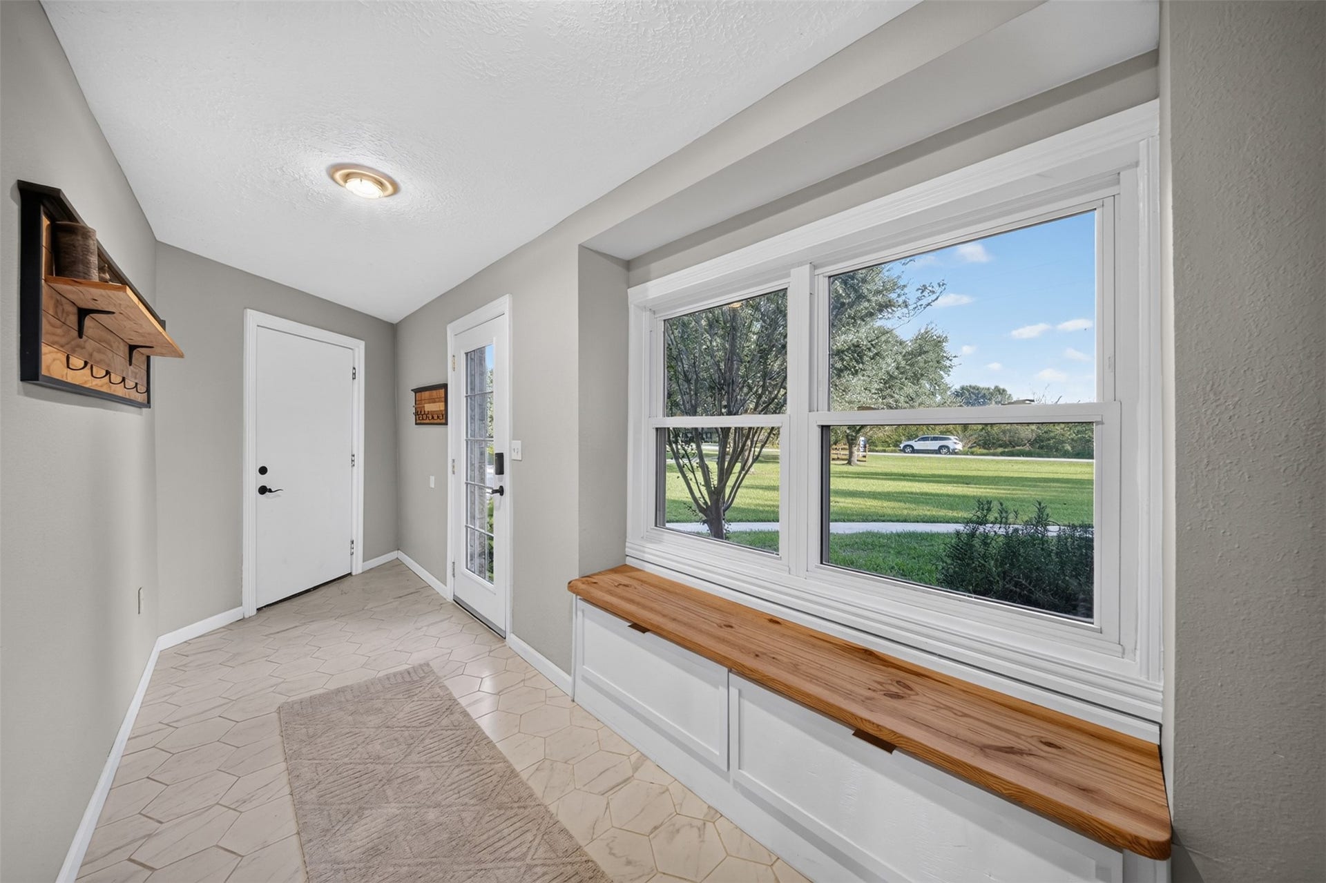 Entry area features a built-in storage bench beneath large windows overlooking the lawn.