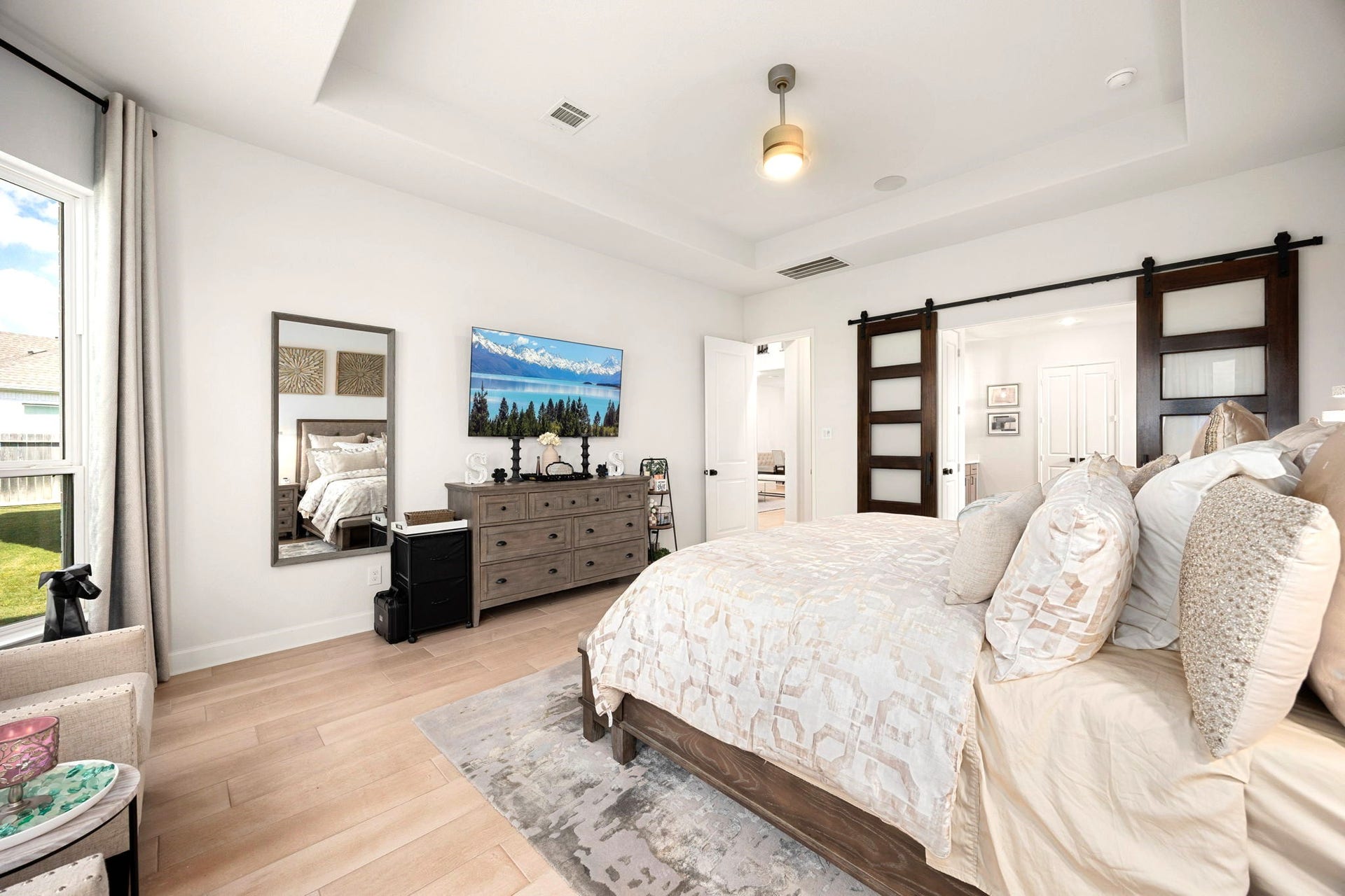 3026 Emerald Field Lane, Fulshear, TX 77423 Elegant double sliding barn doors create a striking transition from the spacious primary bedroom to the luxurious ensuite bathroom, adding custom architectural character and a sophisticated modern touch to the private retreat.