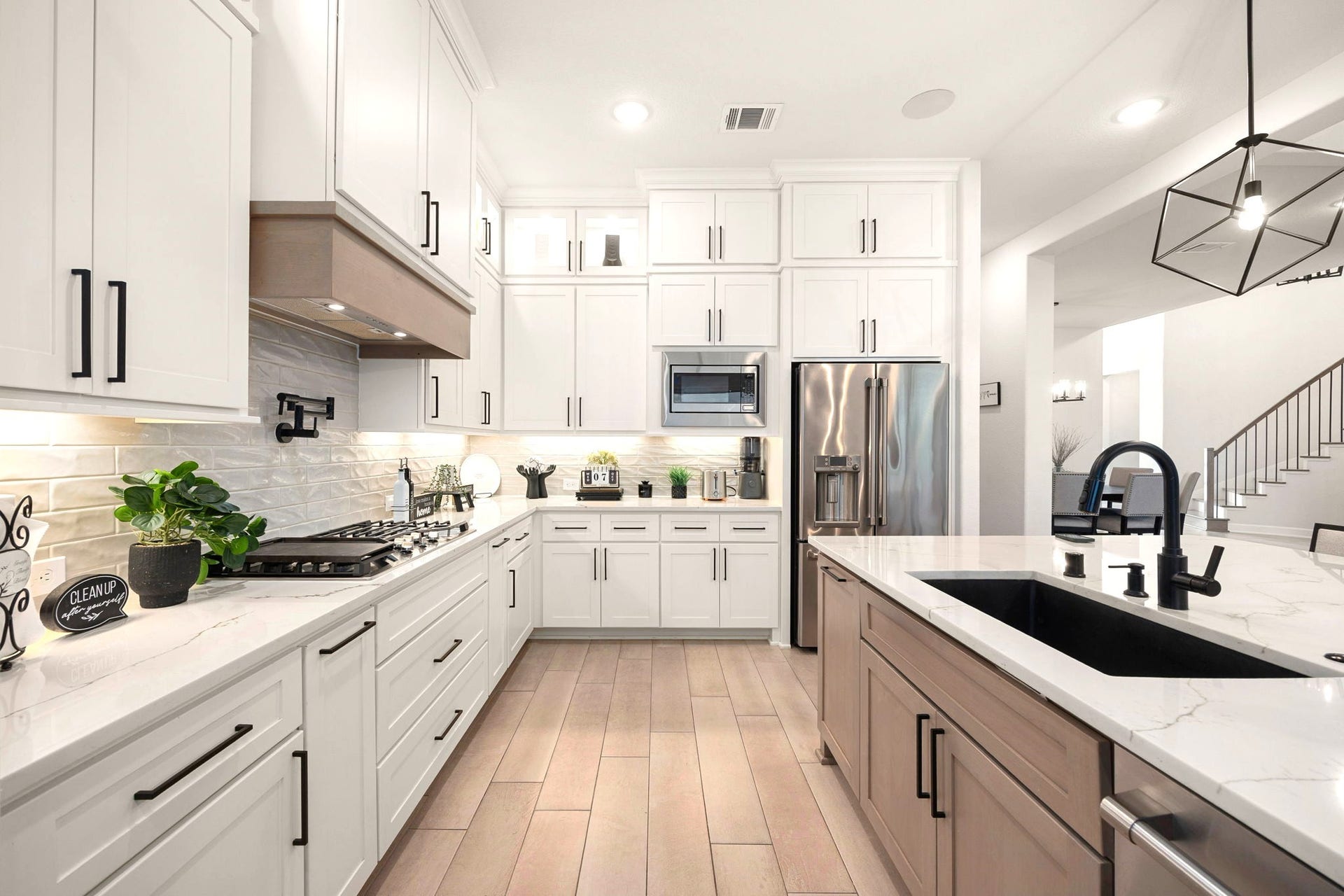 3026 Emerald Field Lane, Fulshear, TX 77423 A chef-inspired kitchen showcases an upgraded vented range hood, convenient pot filler above the cooktop, and a sophisticated black stone sink, combining premium finishes with thoughtful functionality for elevated everyday living and entertaining.