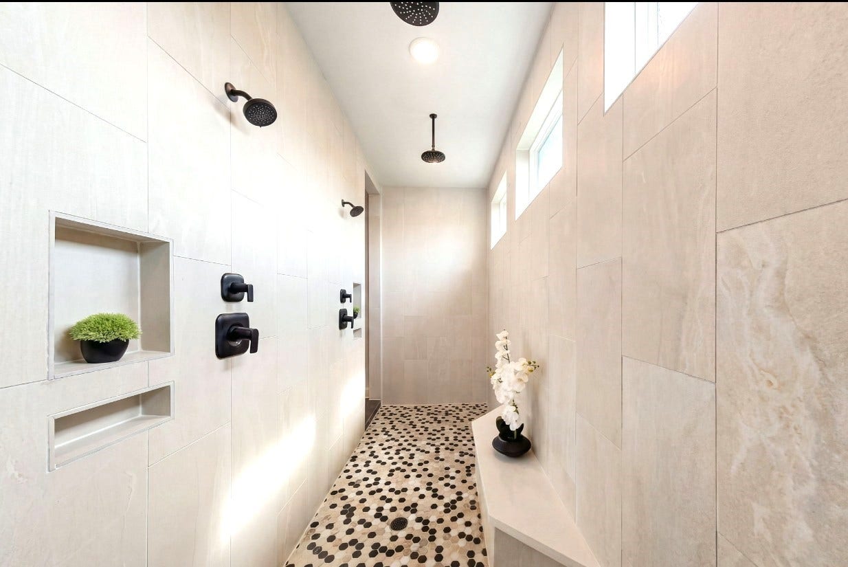 3026 Emerald Field Lane, Fulshear, TX 77423 An expansive spa-inspired shower features elegant honeycomb tile, a built-in shower niches and bench, and four upgraded showerheads, including dual overhead rain showers and two wall-mounted showerheads with dual controls for a luxurious, customized bathing experience.
