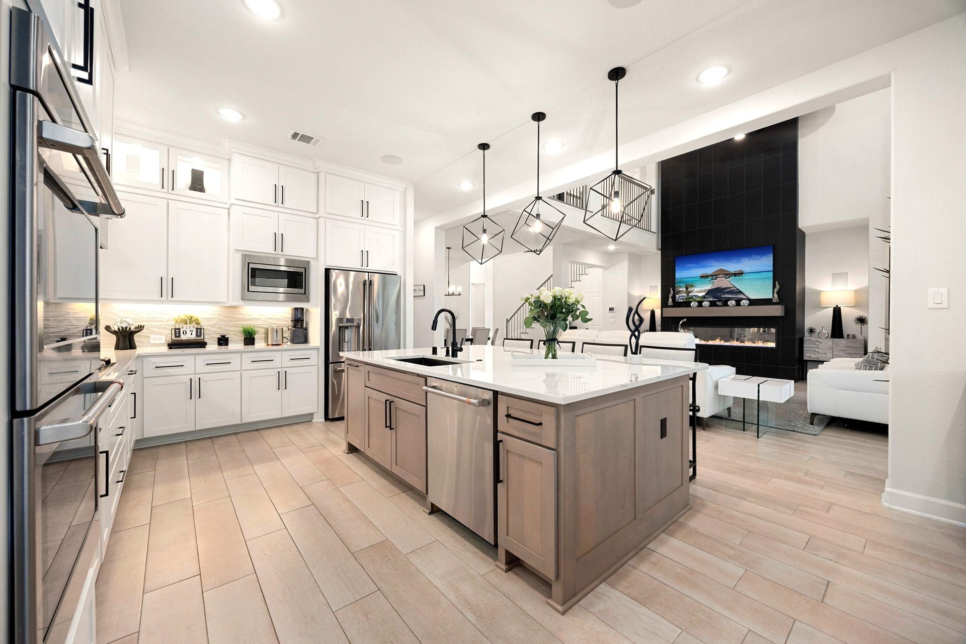 3026 Emerald Field Lane, Fulshear, TX 77423 Elegant upper cabinetry with accent lighting, under-cabinet illumination, and stylish pendant lights above the oversized island create a beautifully layered kitchen ambiance that blends modern sophistication with functional luxury.