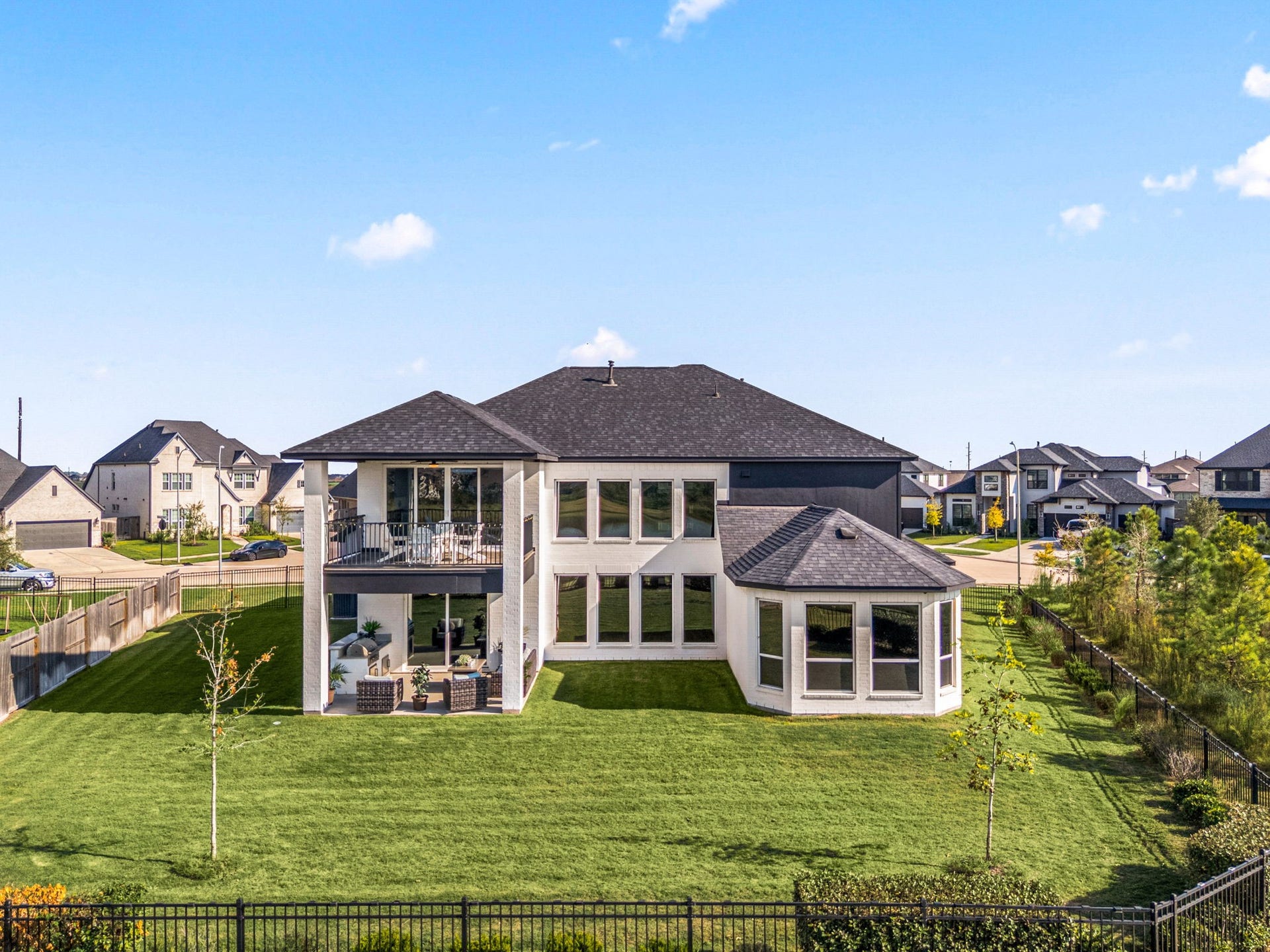 3026 Emerald Field Lane, Fulshear, TX 77423 A stunning aerial view showcases the expansive backyard and both covered outdoor living patios, thoughtfully positioned on the first and second floors to maximize lake views and create exceptional spaces for outdoor entertaining and relaxation.