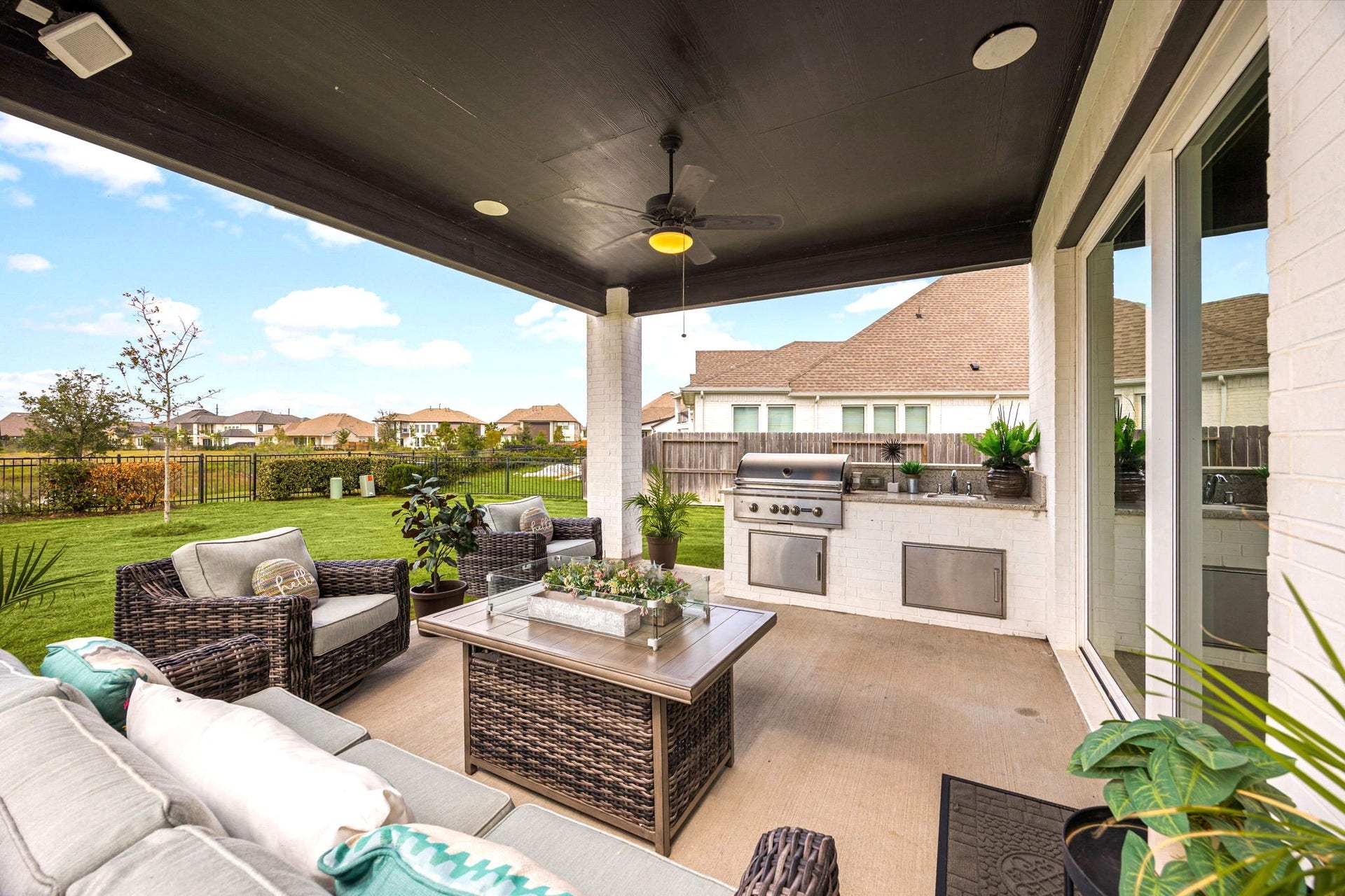 3026 Emerald Field Lane, Fulshear, TX 77423 An upgraded covered outdoor living space features a built-in grill, sink, ceiling fan, and inviting fire pit, creating the perfect setting for year-round entertaining, relaxed evenings, and elevated outdoor living.