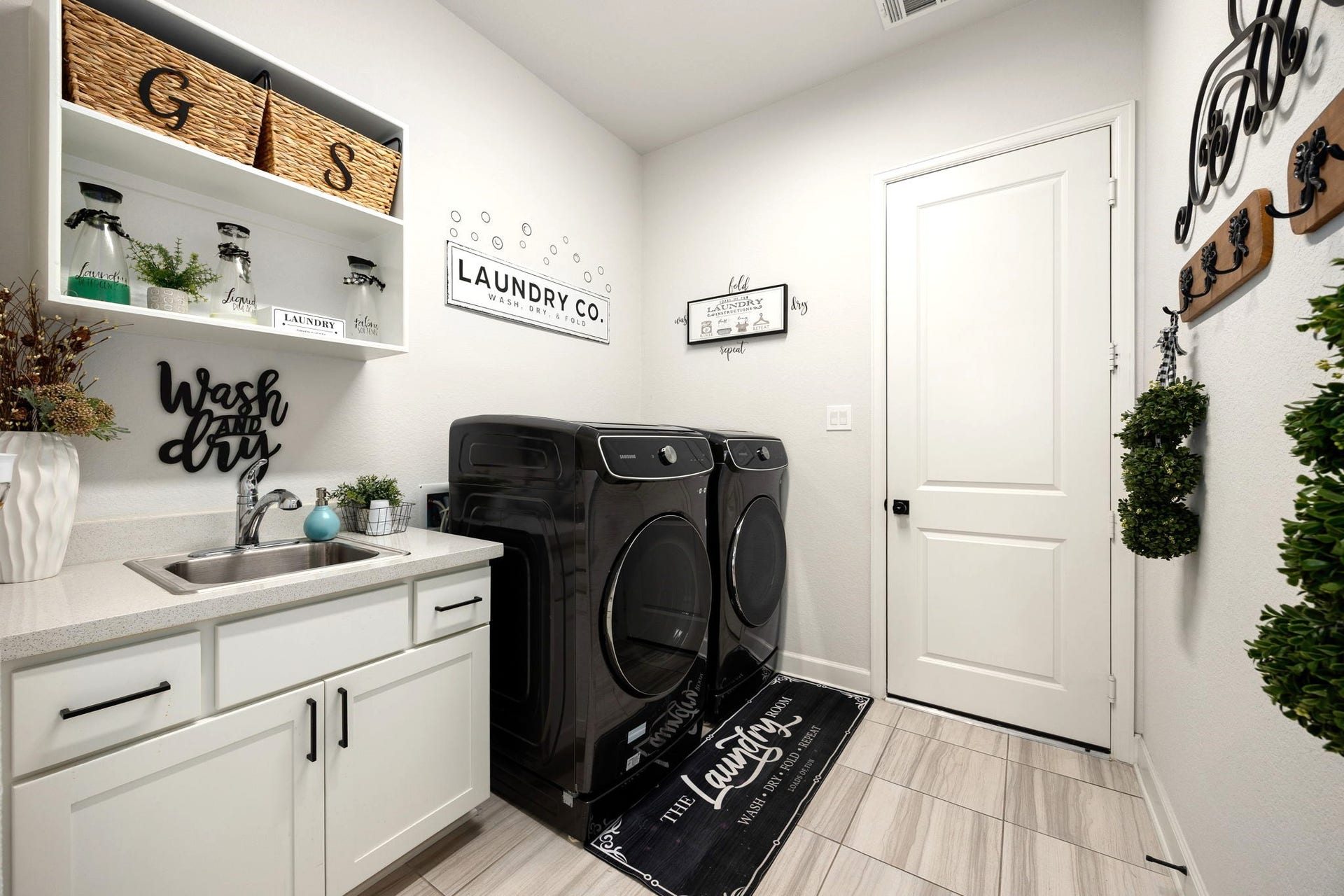 3026 Emerald Field Lane, Fulshear, TX 77423 An expansive laundry room features a custom-added sink, upgraded cabinetry, and drawers for exceptional storage and functionality, with convenient direct access to the impressive four-car garage for everyday ease and organization.