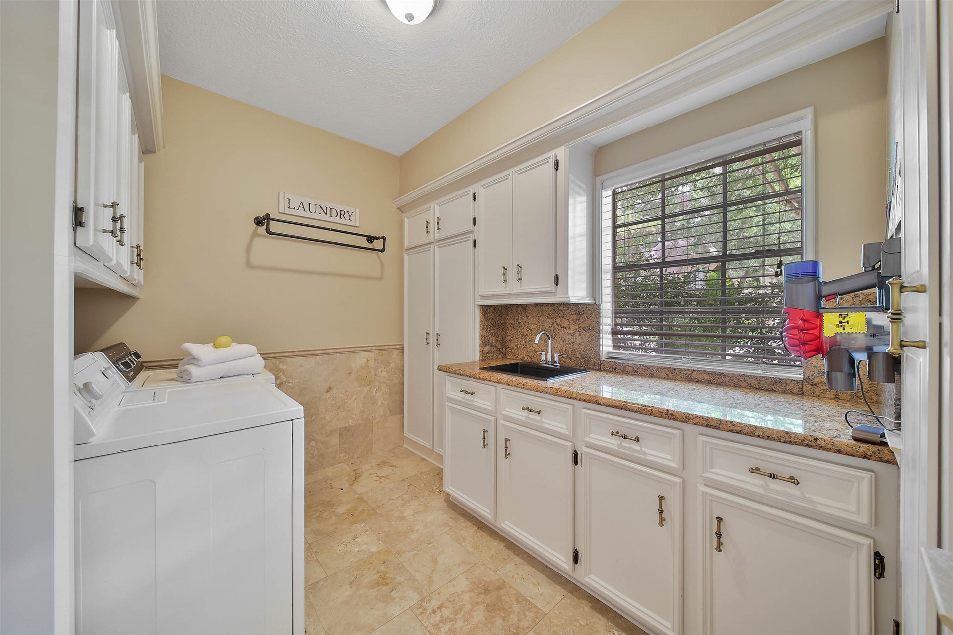 Oversized utility room provides substantial cabinetry, counter space and utility sink.