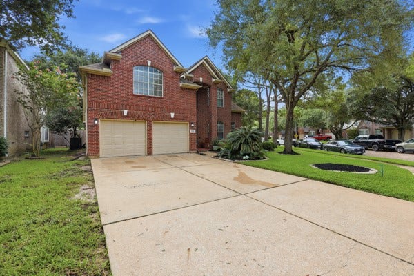 1211 Ragsdale Lane, Katy, TX 77494 Charming two-story brick home with a spacious driveway and double garage, nestled in a lush, green neighborhood.
