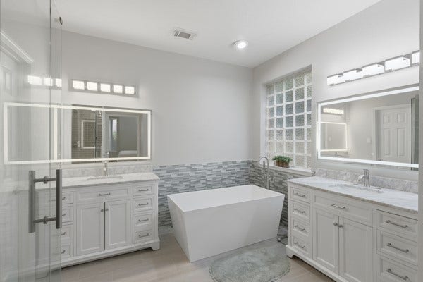 1211 Ragsdale Lane, Katy, TX 77494 Elegant bathroom featuring a freestanding soaking tub, dual vanities with marble countertops, and modern lighting.