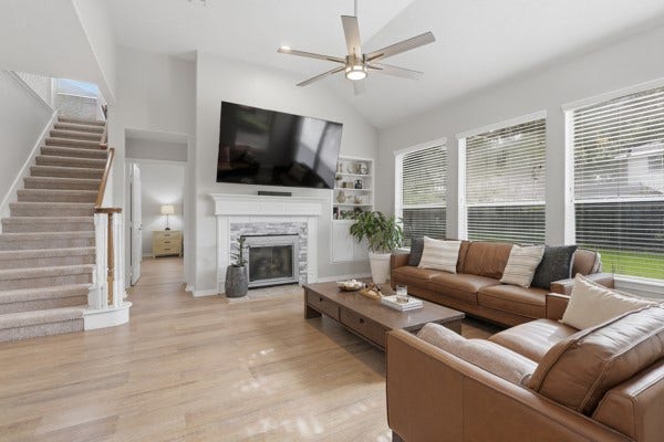 1211 Ragsdale Lane, Katy, TX 77494 Spacious living room with high ceilings, featuring a cozy fireplace, modern ceiling fan, and abundant natural light from large windows.