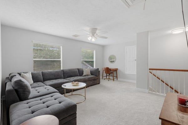 1211 Ragsdale Lane, Katy, TX 77494 Spacious and bright living area featuring a large sectional sofa, modern ceiling fan, and a cozy workspace, perfect for relaxation and productivity.