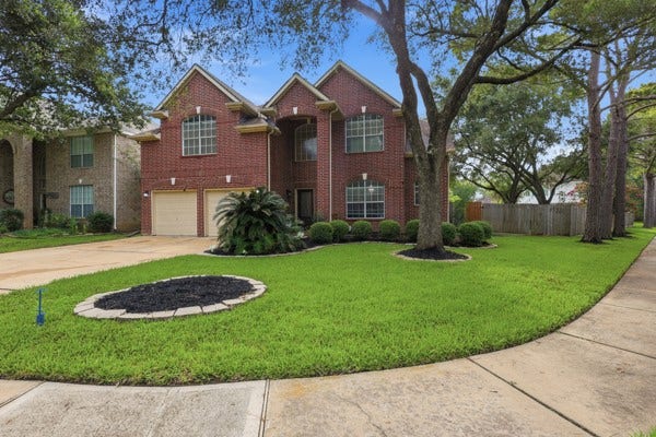 1211 Ragsdale Lane, Katy, TX 77494 Stunning two-story brick home with elegant gables, a manicured lawn, and mature trees, offering charming curb appeal in a serene neighborhood setting.