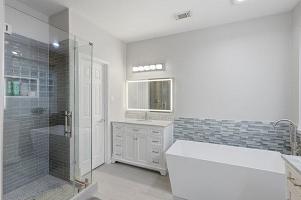 1211 Ragsdale Lane, Katy, TX 77494 Elegant bathroom featuring a sleek glass-enclosed shower, modern soaking tub with stylish tile backsplash, and a chic vanity with ample storage.