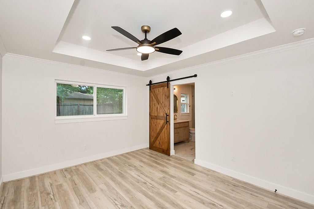 6106 Rutherglenn Drive, Houston, TX 77096 Additional bedroom featuring updated flooring, tray ceilings, and modern finishes.