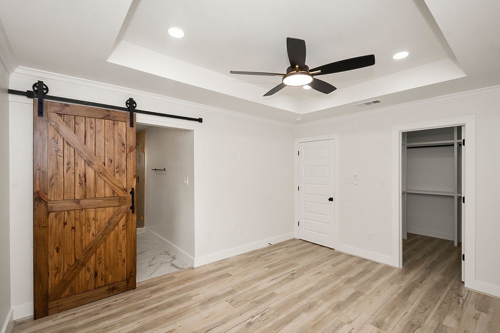 6106 Rutherglenn Drive, Houston, TX 77096 Another view of the beautifully updated primary suite showcasing tray ceilings and modern barn door accents.