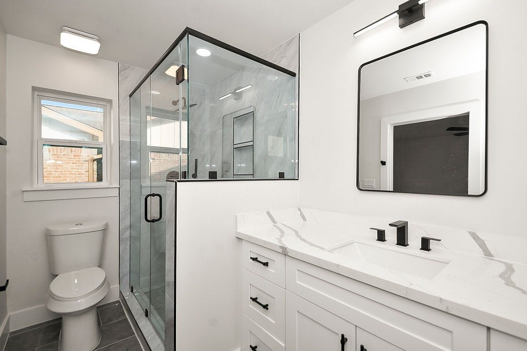 6106 Rutherglenn Drive, Houston, TX 77096 Beautifully updated bathroom featuring modern vanity, sleek fixtures, and glass-enclosed shower.