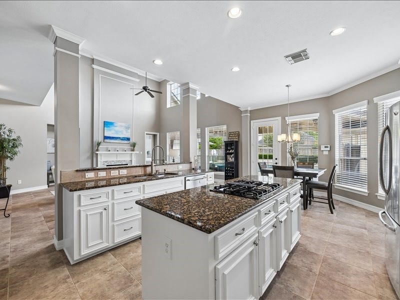 9007 Avebury Stone Circle, Missouri City, TX 77459 A spacious kitchen featuring an oversized center island with a 4-burner gas cooktop, rich dark granite countertops, and ample workspace for entertaining at any scale.