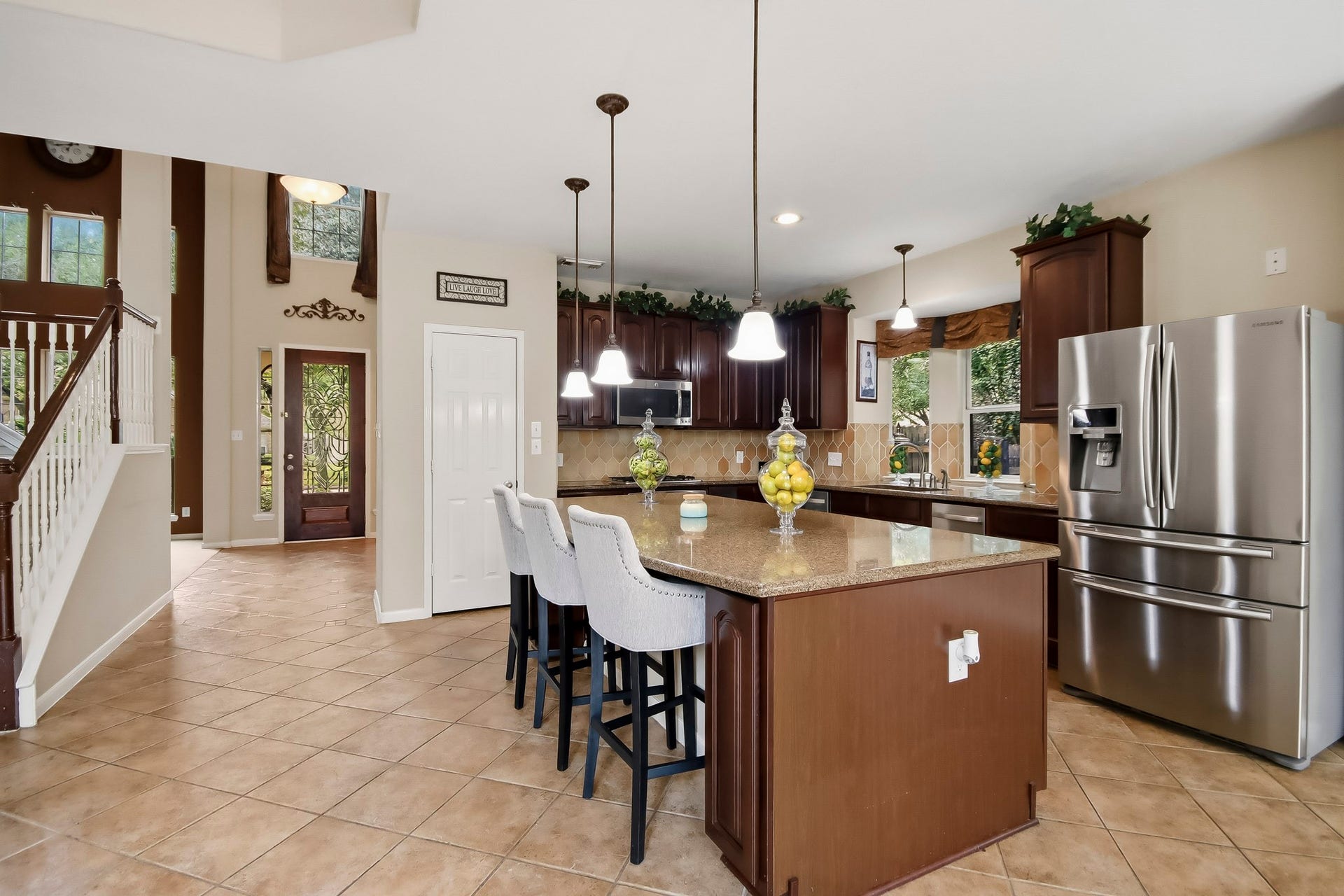 Beautiful open-concept kitchen featuring granite countertops, elegant pendant lighting, and a spacious island perfect for gathering and entertaining. Refrigerator and three bar stools included with the sale of the home!