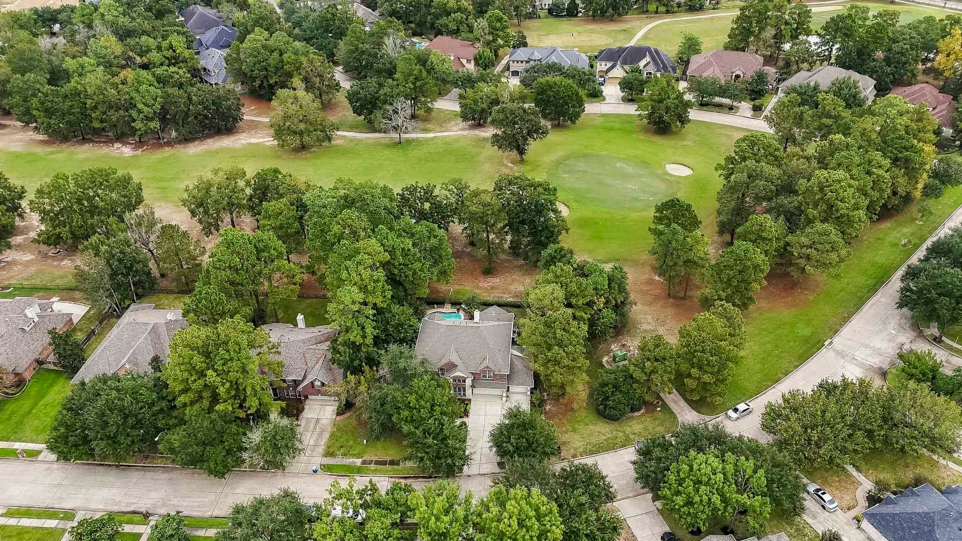 Another stunning birds-eye view showcasing the homes prime location overlooking the 10th hole of the golf course, surrounded by lush greenery and mature trees.