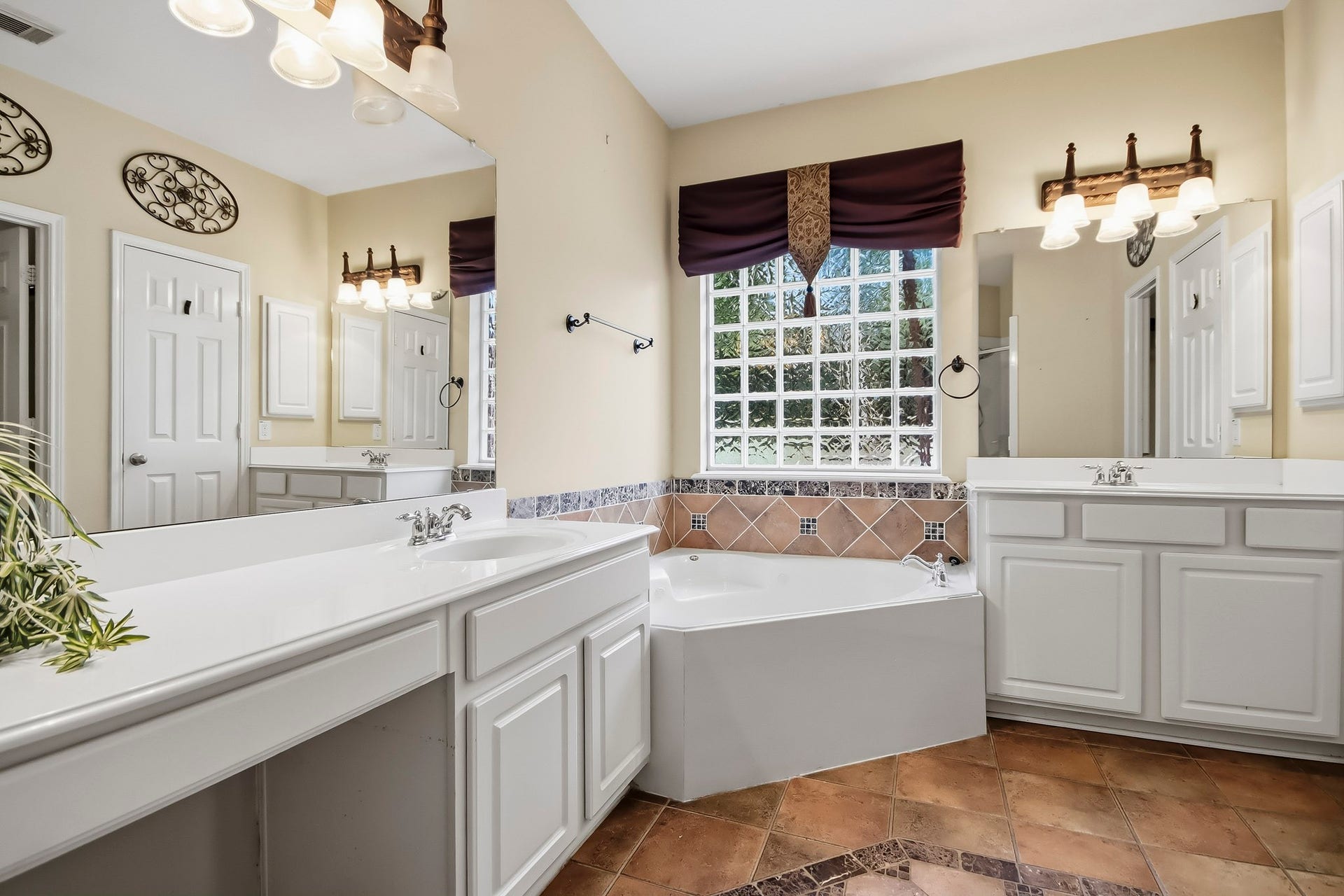 Spacious primary bathroom featuring a relaxing soaking tub and generously spaced vanities, offering plenty of countertop space, storage, and comfort for your daily routine.